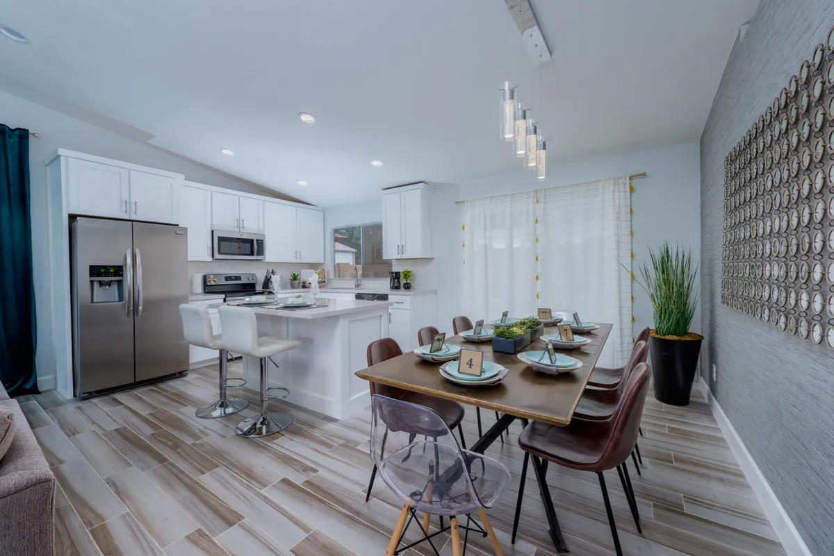 This image showcases a contemporary dining table setup with modern kitchen appliances and decorative wall art. The scene is bright, inviting, and features thoughtful touches that suggest readiness for family meals or gatherings, as well as practical amenities for everyday living.