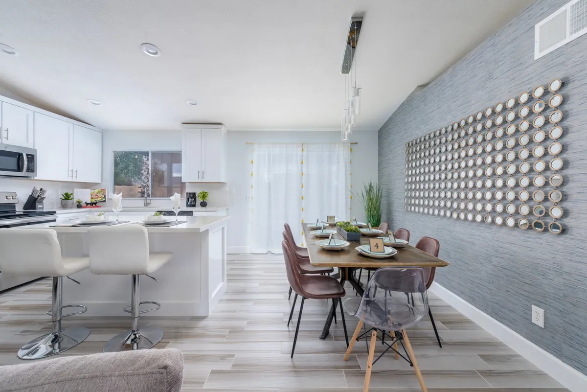 A bright, inviting interior featuring a kitchen island with seating, a dining table, and stylish wall art. The layout is ideal for socializing, sharing meals, or enjoying cooking sessions with family and friends.