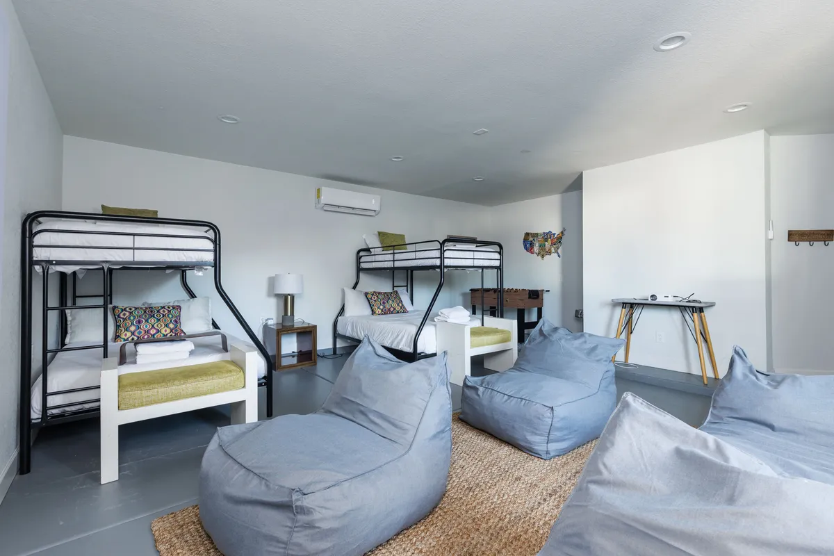 A cheerful kids' room featuring bunk beds, colorful bean bag chairs, a cozy rug, decorative pillows, and a side table. The playful decor and relaxed layout make it ideal for families traveling with children or groups needing versatile sleeping arrangements.